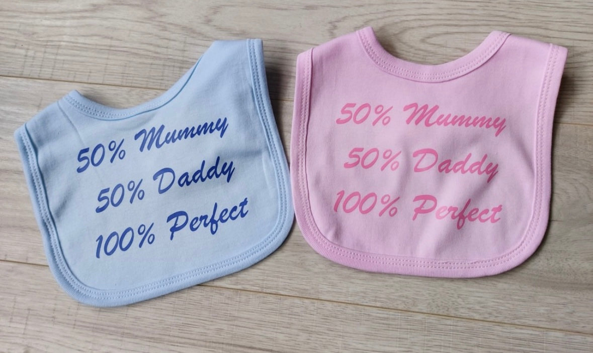 ''50% mummy, 50% Daddy, 100% perfect'' baby bib in white, pink or blue.